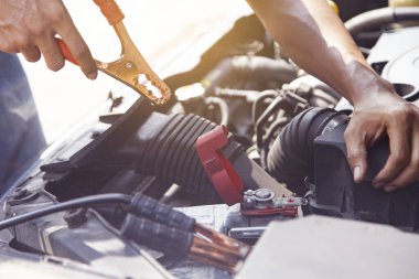 Ölü bir batarya üzerinde şarj kablosu kullanan bir adam.