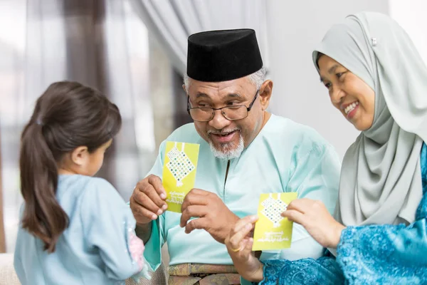 Starsza Muzułmańska Para Pokazując Zielone Koperty Swojej Wnuczce — Zdjęcie stockowe