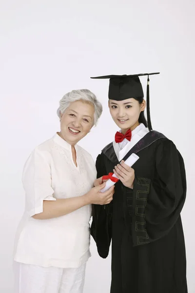 Mujer Bata Graduación Con Pergamino Posando Con Una Mujer Mayor — Foto de Stock