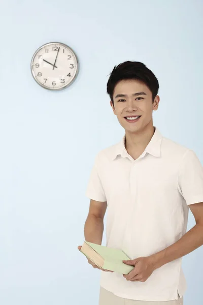 Uomo Sorridente Mentre Tiene Libro Orologio Sul Muro — Foto Stock