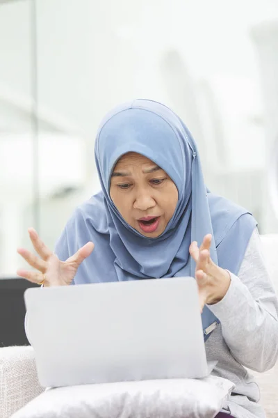 Senior woman is shocked looking at laptop screen