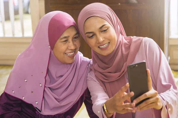 Malay woman taking self-photograph with her parent