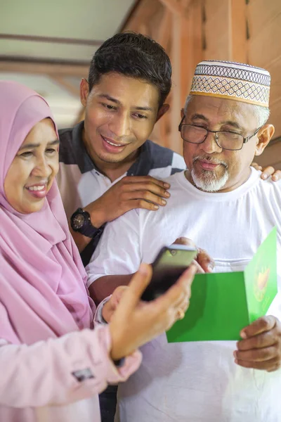 Eidグリーティングカードを持っている両親と息子はスマートフォンを見て — ストック写真