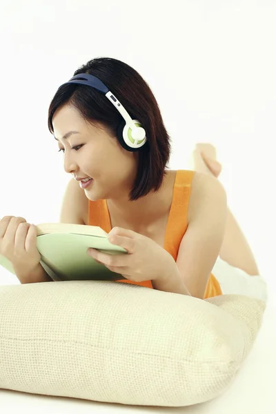 Kobieta Słuchająca Słuchawek Podczas Czytania Książki — Zdjęcie stockowe