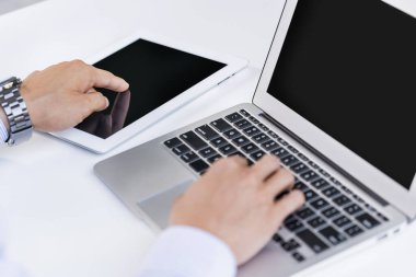 Laptop ve tablet bilgisayarla çalışan bir adam