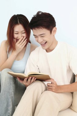 Erkek ve kadın kitap okurken gülüyorlar.