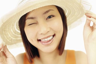 Hasır şapkalı kadın göz kırpıyor ve dilini dışarı çıkarıyor.