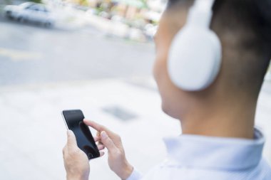 Telefonunu kullanarak kulaklıkla müzik dinleyen bir adam.