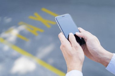 Taksi çağırmak için mobil uygulama kullanan bir adam.
