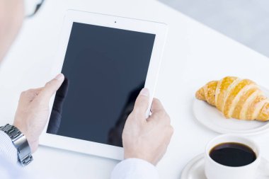 Elinde tablet bilgisayar tutan bir adam.