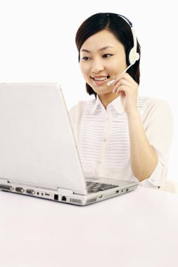 Laptop kullanan kulaklıklı bir iş kadını.