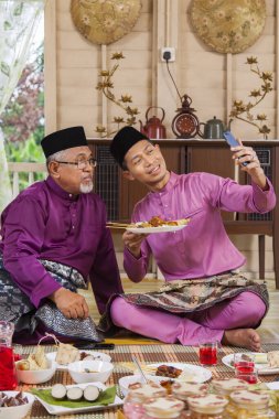 Malezyalı adam ailesiyle fotoğraf çekiyor.