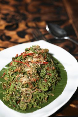 Acı biberli, karamelli hindistan cevizli ve karidesli yabani eğreltiotu kızartması.