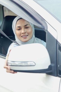 Kadın dikiz aynasını ayarlıyor.