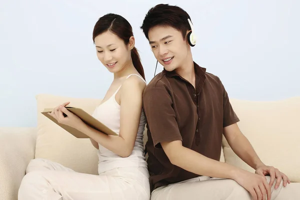 Άντρας Που Ακούει Μουσική Στα Ακουστικά Γυναίκα Που Διαβάζει Βιβλίο — Φωτογραφία Αρχείου