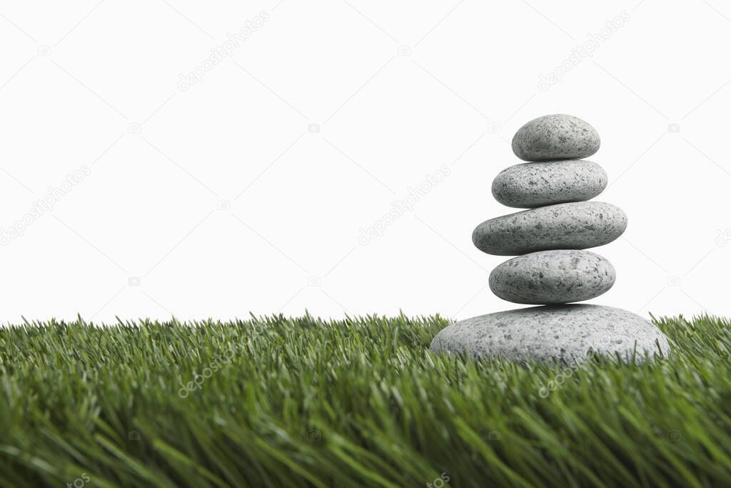 Five stones stacked up on grass