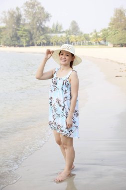 Plajda poz veren hasır şapkalı kadın.