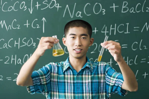Young man holding laboratory flask and test tube