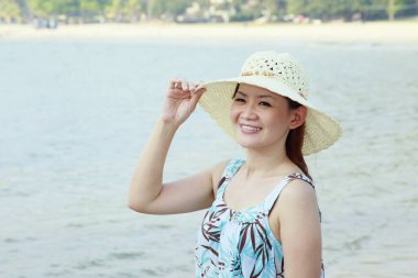 Kumsalda poz veren şapkalı kadın.