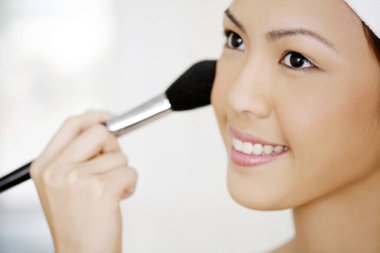 Yanağına allık süren bir kadın.