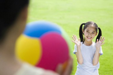 Anne ve kızı parkta top oynuyorlar.