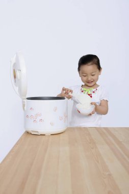 Pirinç pişiriciden pirinç kepçesi çıkaran kız.