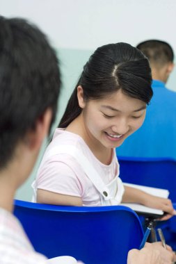 Üniversite öğrencileri sınıfta sohbet ediyorlar.