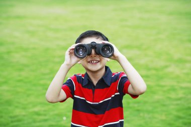 Çocuk parkta dürbünle oynuyor.