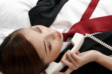 İş kadını yatakta yatarken telefonda konuşuyor..