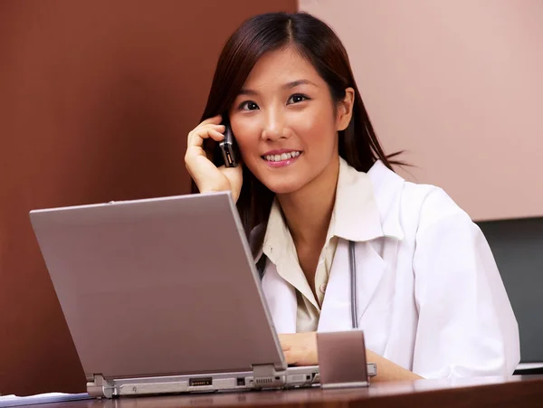Doctor Using Laptop While Talking Handphone — Stock Photo, Image