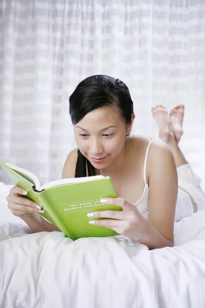 女人躺在床上看书 — 图库照片