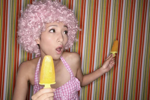 Woman holding two ice lollies, looking surprised