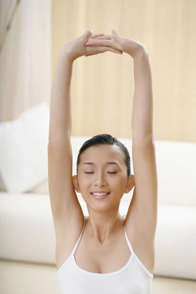 Woman stretching her arms upwards with her eyes closed