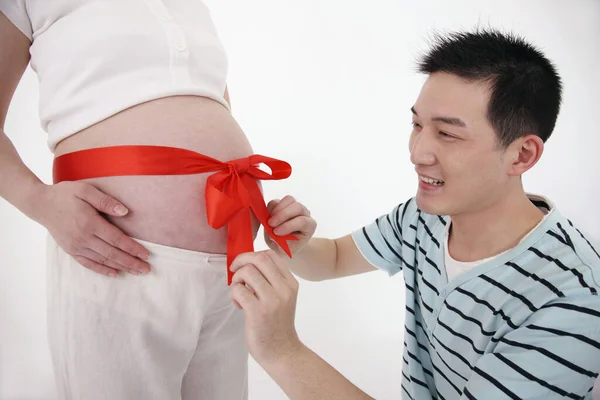 Man Tying Red Ribbon Tied Pregnant Woman Stomach — Stock Photo, Image