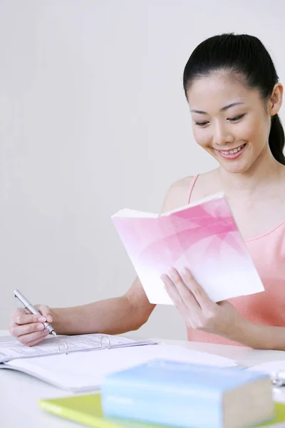 Woman Reading Book While Writing — Stock Photo, Image