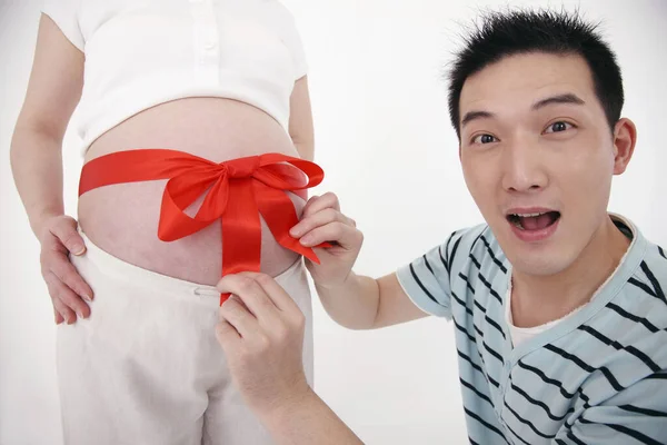 Man Tying Red Ribbon Tied Pregnant Woman Stomach — Stock Photo, Image