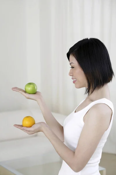 Mujer Sosteniendo Manzana Naranja Cada Mano —  Fotos de Stock