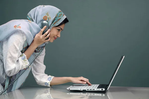 ラップトップを使用している間に電話で話す伝統的な服のビジネスマン女性 — ストック写真