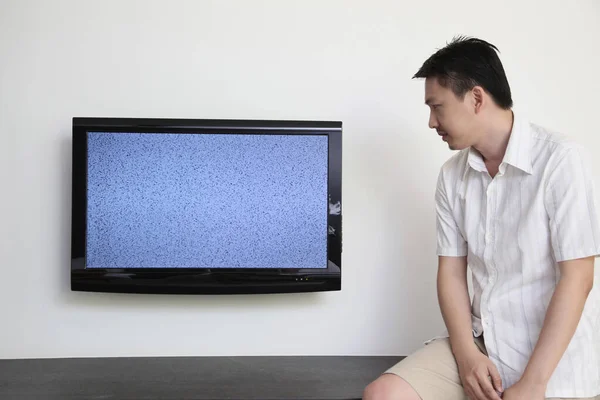 Man looking at ruined television in sadness