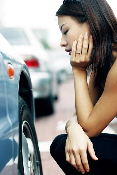 Woman looking at the flat tire with frustration.