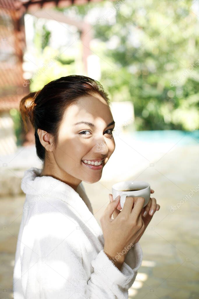 Woman in bathrobe enjoying a cup of coffee
