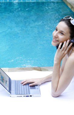 Laptop kullanan bir kadın telefonda konuşuyor.