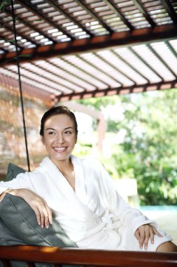 Bornozlu kadın salıncakta rahatlıyor.