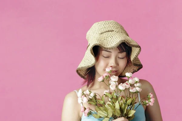 Kobieta Kapeluszem Pachnące Kwiaty — Zdjęcie stockowe