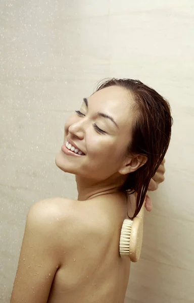 Woman using body brush in the shower