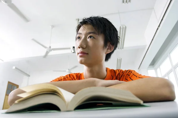 Young man daydreaming while studying