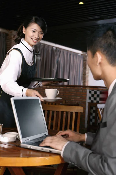 Empresario Usando Laptop Camarera Sirviéndole Una Taza Café —  Fotos de Stock