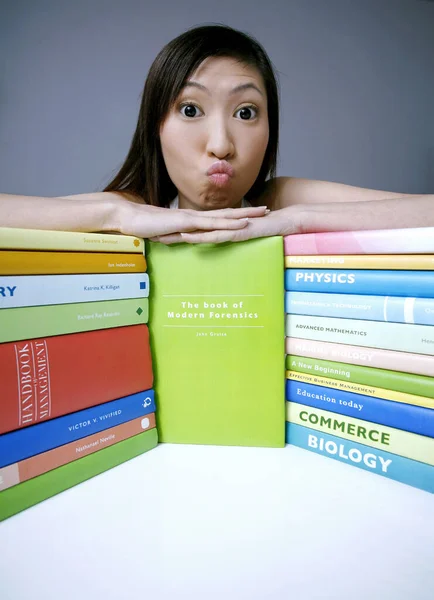 Vrouwelijke Student Maakt Een Gezicht Terwijl Poseren Met Gestapelde Boeken — Stockfoto