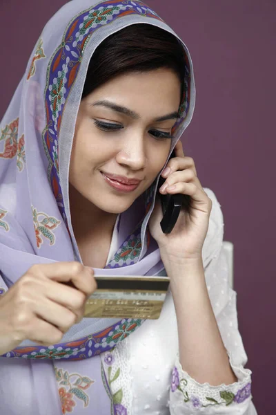 電話で話している間にクレジットカードを参照して伝統的な服のビジネスマンの女性 — ストック写真