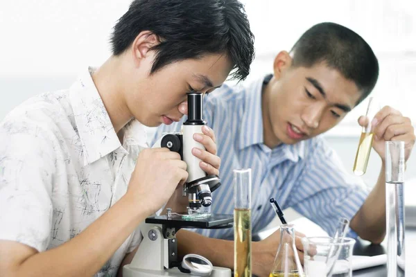 Young Man Looking Microscope His Course Mate Making Notes — Stock Photo, Image